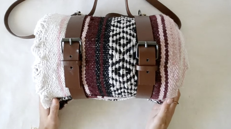 Dolaba asılmaya hazır, deri kayışlarla sarılmış bir battaniye.