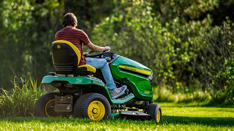 John Deere X354 binicili çim traktörü kullanan kişi