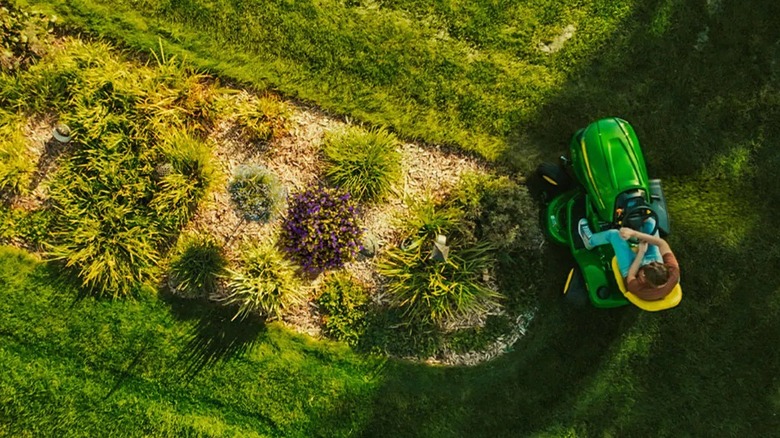 John Deere X354 binicili çim traktörü kullanan kişi