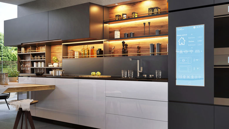 İyi organize edilmiş mutfak eşyaları ve cihaz kontrolü için akıllı ekran içeren gri ve beyaz mutfak dolapları