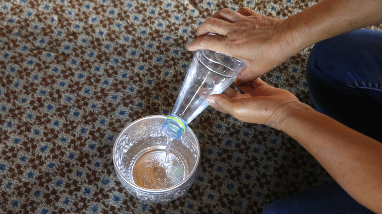 küçük bir kaba su döken kişi