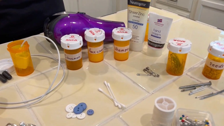 Çeşitli eşyaların ve etiketli hap şişelerinin bulunduğu banyo fayansı etrafa yayılmış