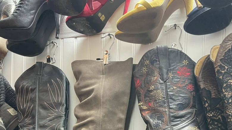 Bir dolabın duvarına çakılmış çivilerle pantolon klipslerinden sarkan botlar.