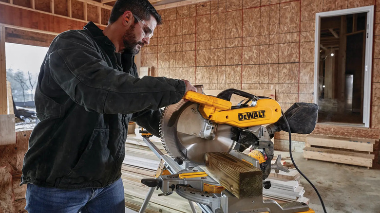 Bir ev projesinde DeWalt Çift Eğimli Bileşik Kablolu Gönye Testereyi kullanan bir adam 4'e 4'lük bir kesiti kesiyor