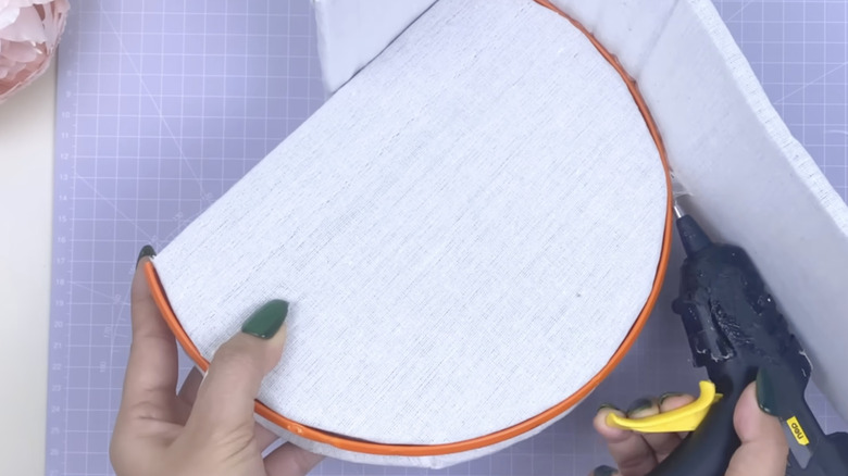 Bir kişi DIY kutusunun döşemeli tarafını tabana yapıştırıyor.