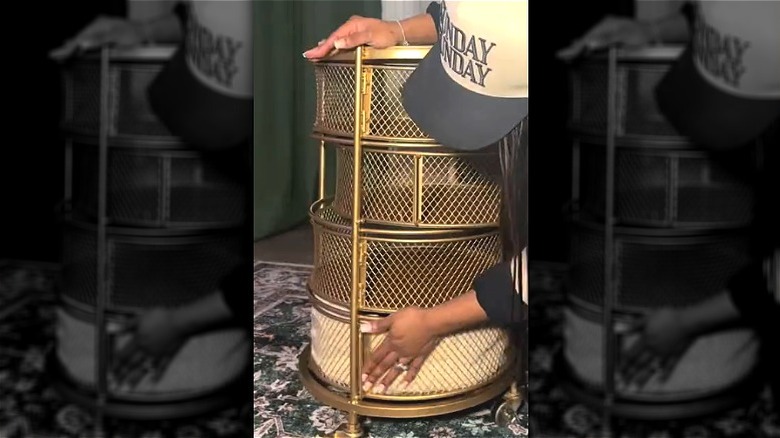 Alt rafta battaniyeyle altın rengi metal katmanlı depolama arabasına dokunan kişi