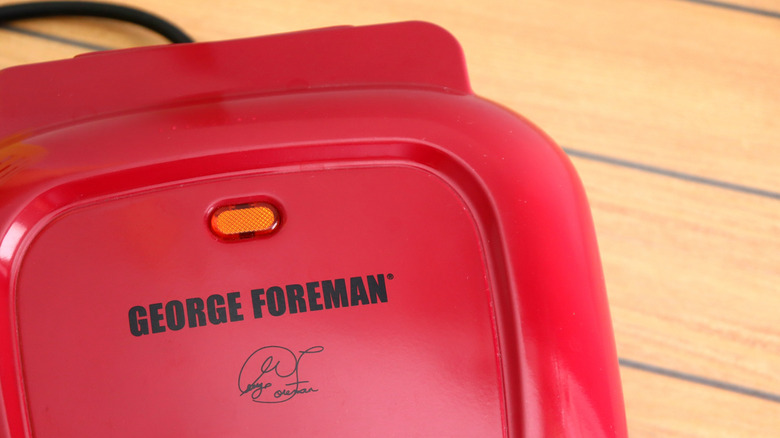 Ahşap bir tezgahın üzerinde kırmızı bir George Foreman ızgarası.