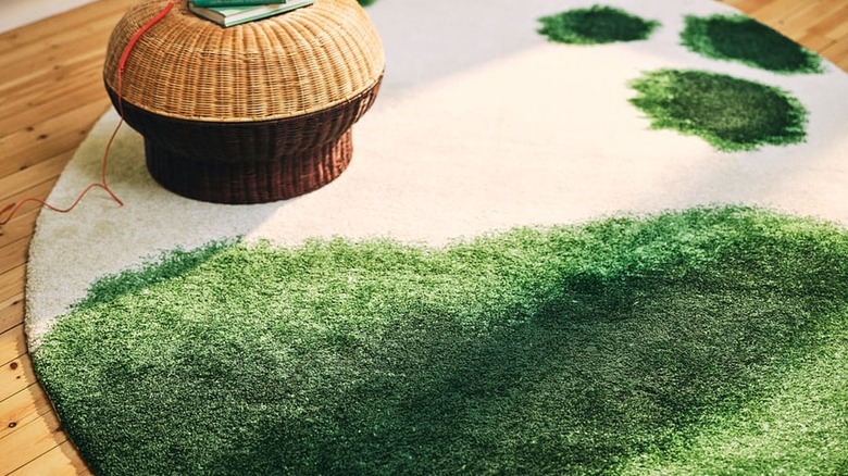Rattan ayak taburesi ile yerde yeşil ve kirli beyaz halı