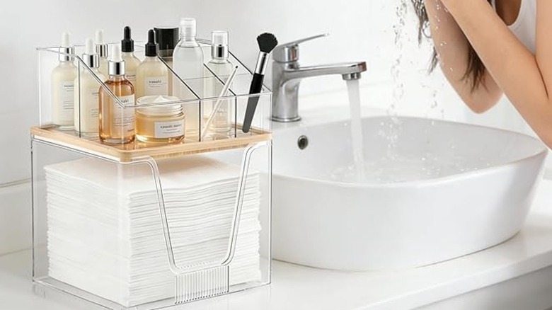 Banyo tezgahındaki akrilik makyaj düzenleyicinin altında yüz havlusu tutucusu
