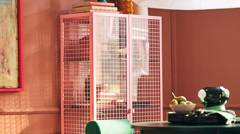 Pembe ızgara desenli cam IKEA dolabı, eşyaları rahat bir odada saklıyor.