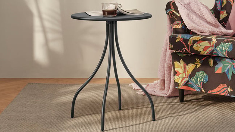 IKEA'nın yan sehpasında kanepenin yanına yerleştirilmiş bir vazo ve içecek bulunur.