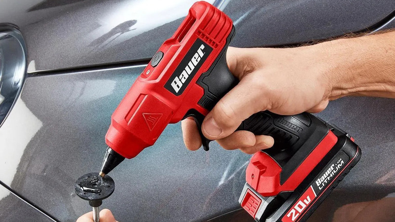Araba parçasını tamir etmek için BAUER 20V Akülü Tutkal Tabancasını kullanan kişi