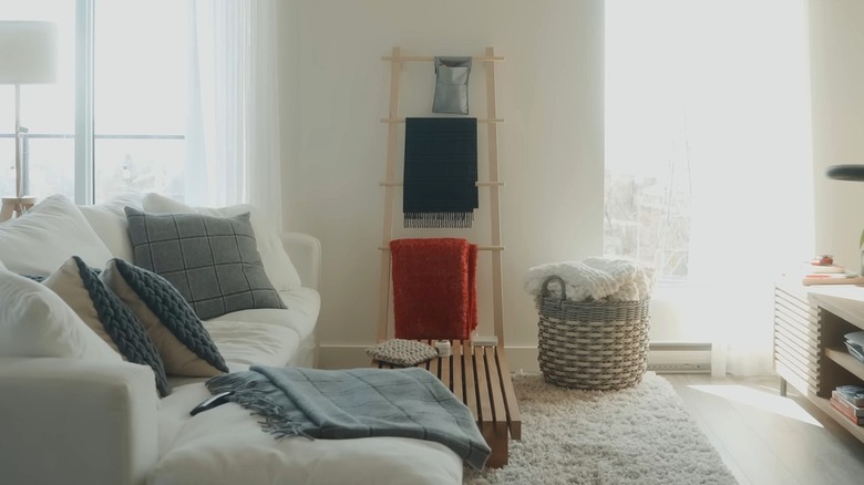Oturma odasında çeşitli battaniyelerin bulunduğu IKEA VILTO havlu standı