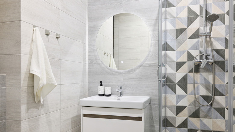 Kancalara asılı havluların olduğu minimalist bir banyo.