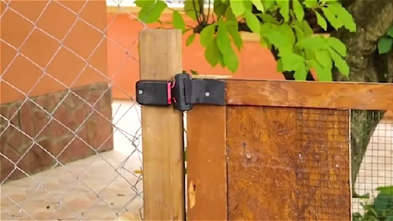 Kontrplak ve zincir bağlantı kapısı, kapı mandalı görevi gören emniyet kemeri tokasıyla kapalı tutuluyor.