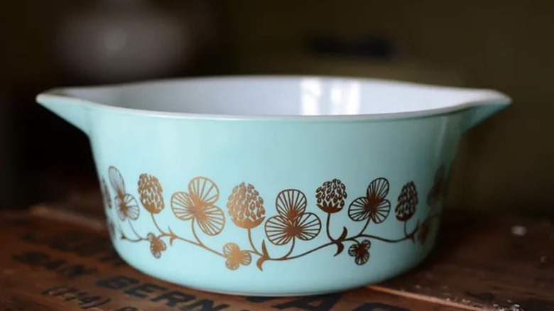 İleri dönüştürülmüş ahşap bir masanın üzerinde bir Clover Berry Pyrex kasesi.