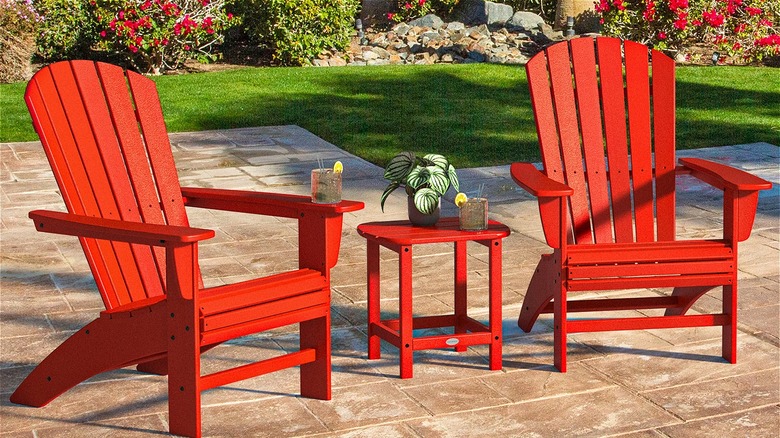 İki kırmızı Adirondack sandalyesi, içecekler ve bir bitki