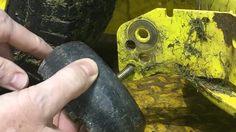 Sürmeli çim biçme makinesi güvertesine kılavuz tekerleği yerleştiren kişi