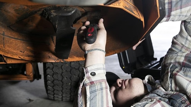 Çim biçme makinesinin güvertesini kazıyan adam