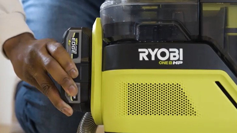 Koyu tenli bir el Ryobi aletine pil takıyor.