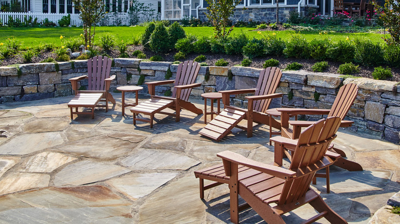 Batık kaldırım taşı veranda alanında beş kahverengi Adirondack sandalye