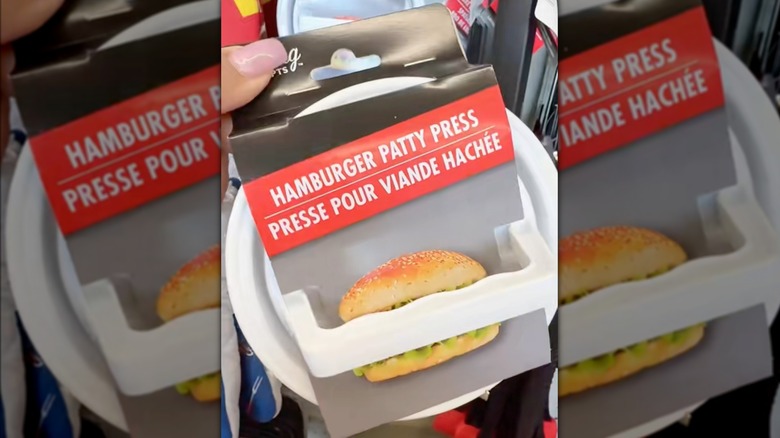 Dollar Tree'de mağazadayken hamburger köftesi presini tutan bir el.