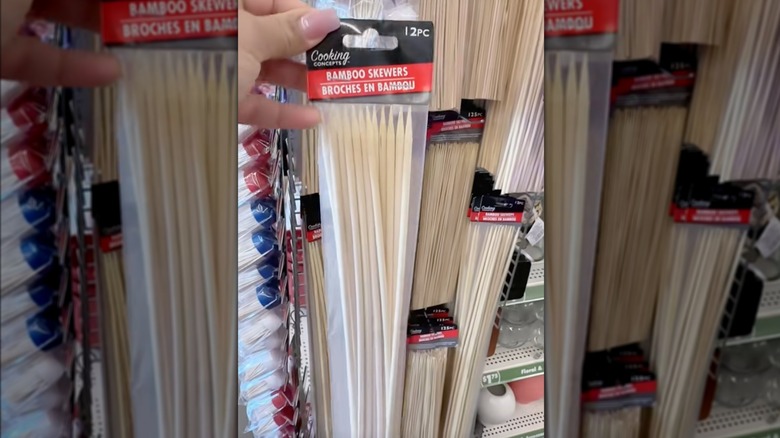 Dollar Tree'deki sergi duvarının önünde bir el bir paket bambu şiş tutuyor.