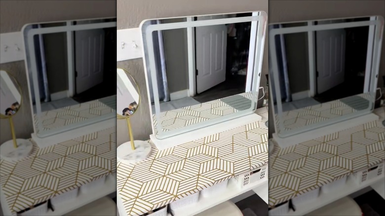 Dekoratif desenli yapışkan raf astarıyla kaplanmış banyo makyaj masası.