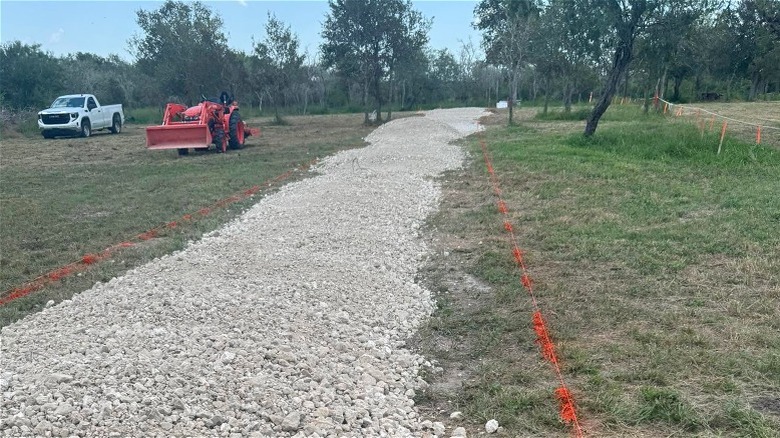 Kuruluma hazır işaretli bir garaj yolu boyunca yığılmış kaliş çakılları.