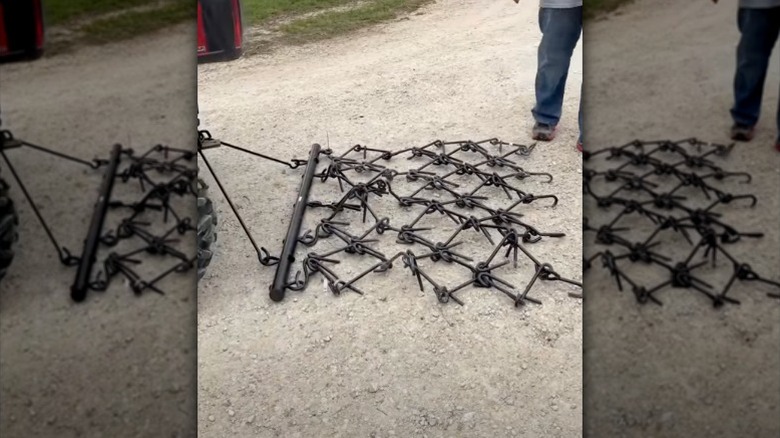 ATV'ye bağlı bir Vevor zincirli tırmık, çakıllı bir araba yolunda duruyor.