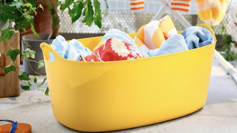 IKEA TORKIS parlak sarı çamaşır sepeti, içinde çeşitli renkli havlular