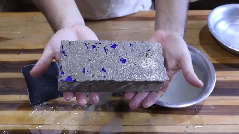 Dekorasyon için cam kırıklarından yapılmış DIY tuğla kaldırım taşı tutan kişi