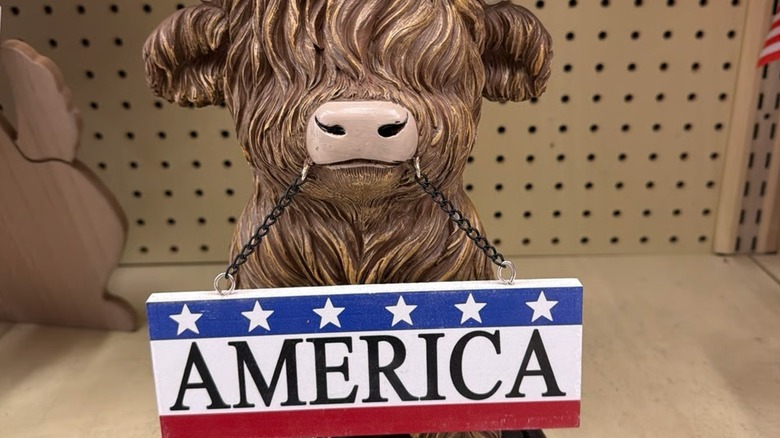 Ağzında üzerinde Amerika yazan bir tabela tutan yayla ineği heykelciği.