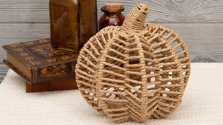 Masanın üzerindeki dekoratif kitapların önüne yerleştirilmiş dokuma hasır balkabağı.