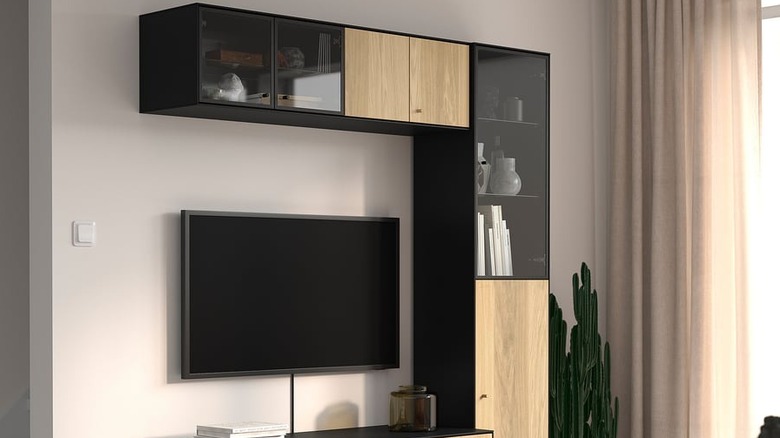 Ortasında TV ve cam bölmelerinde dekorasyon bulunan BOASTAD TV saklama kombinasyonu