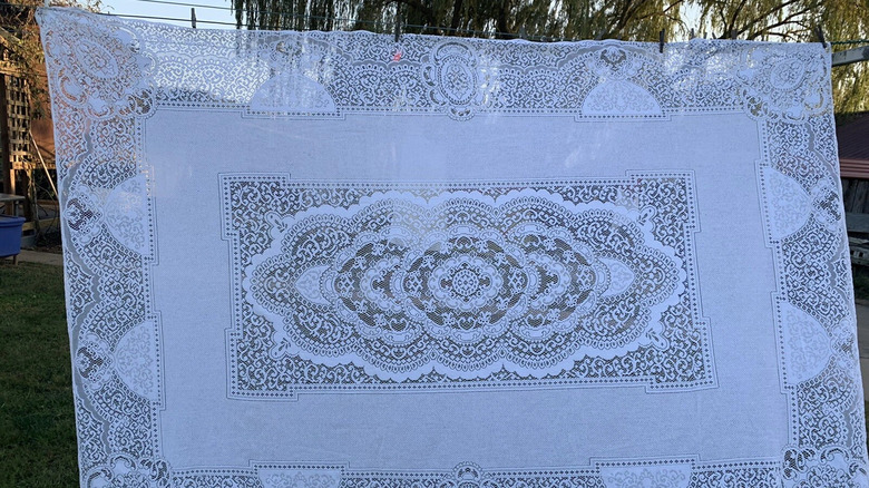 Açık havada çamaşır ipine asılı 1980'lerden kalma polyester pamuklu dantel masa örtüsü