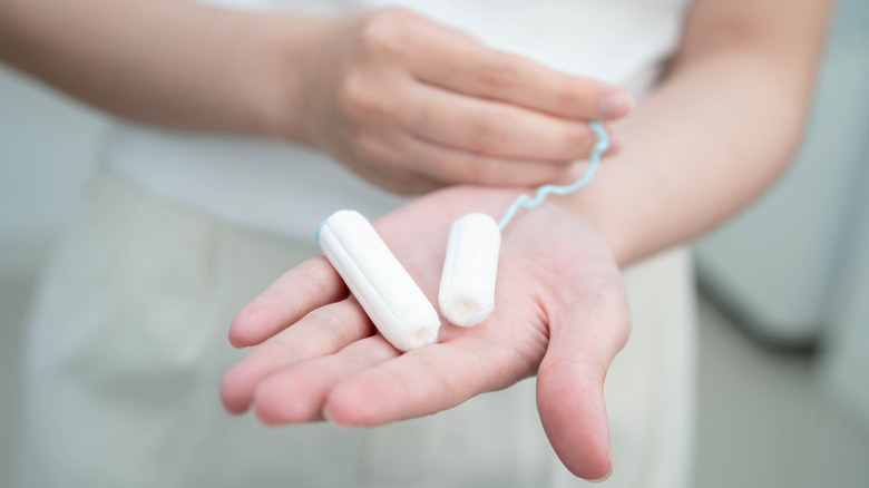 Aplikatörsüz pamuklu tampon tutan bir kadın.