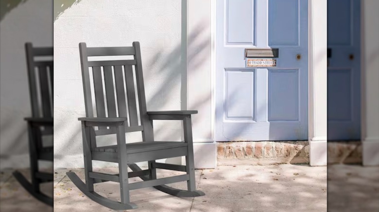 Mavi kapının yanındaki verandada gri Adirondack sallanan sandalye