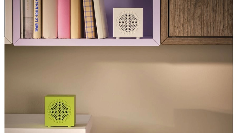 Kitap raflarında duran küçük taşınabilir Bluetooth hoparlörler