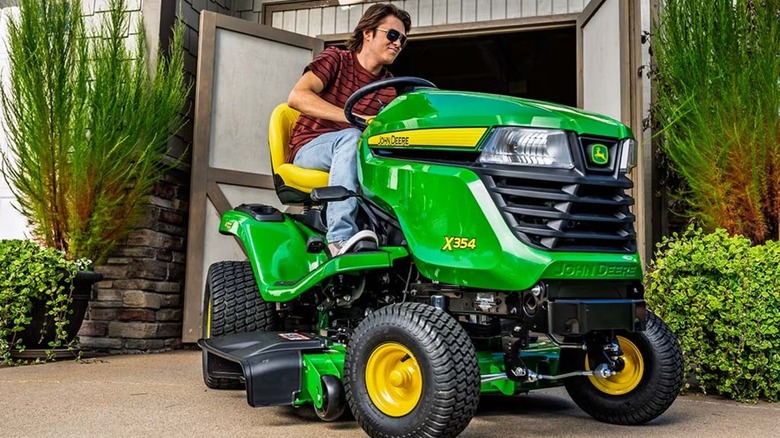 John Deere X354 çim biçme makinesine binen adam