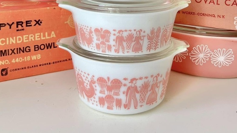 Orijinal ambalaj kutularının yanındaki rafta Pyrex pembe ve beyaz Butterprint tabaklarının yakın çekimi