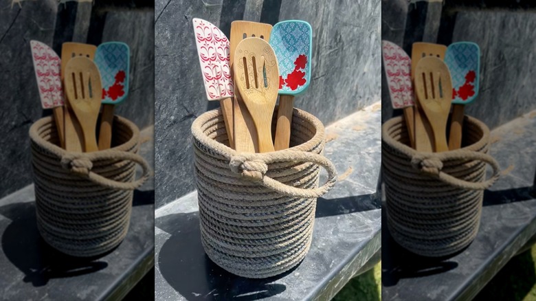 İçinde tahta kaşık ve spatula bulunan el yapımı kement ipi alet tutucusu.