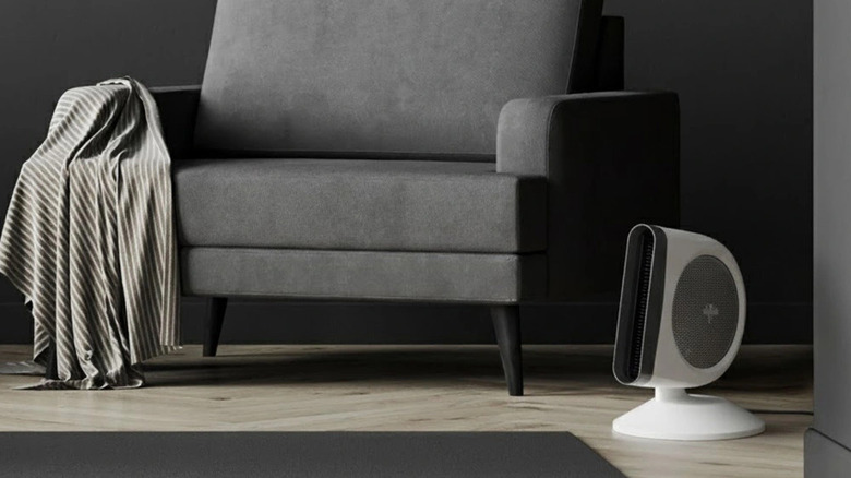 Gri bir koltuğun önünde yerde duran Vornado Strata 8C Omni Fan
