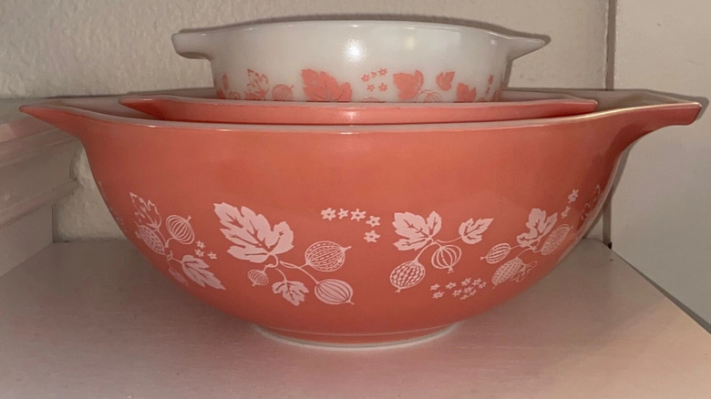 Üç adet Cinderella Bektaşi Üzümü Pyrex kasesinden oluşan bir yığın, krem ​​renkli bir mutfak dolabındaki rafta duruyor.