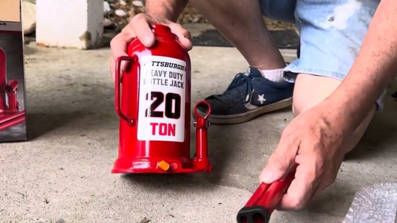 20 tonluk hidrolik şişe krikosu tutan kişi