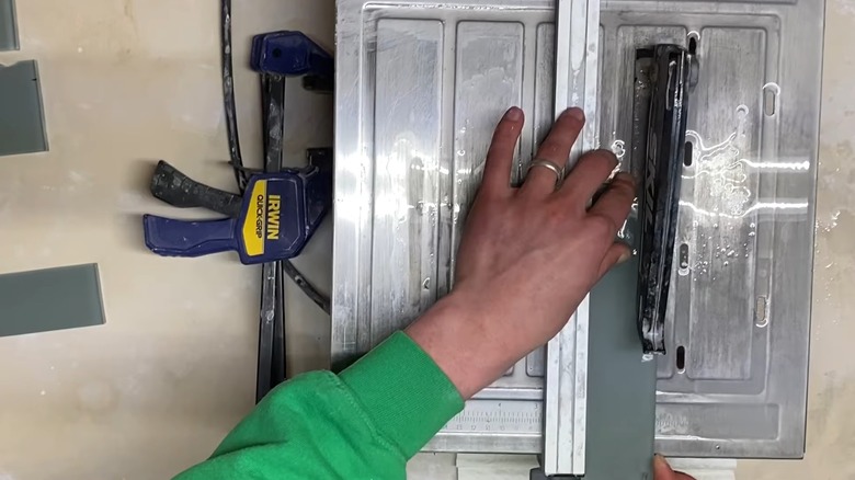 Islak testereyle cam karonun köşesini kesen eller