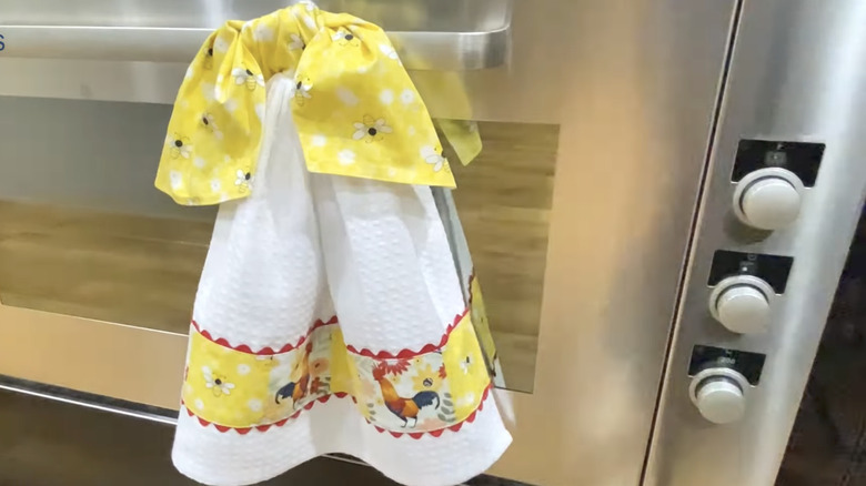 Fırın kapısına DIY kravatlı bir çay havlusu asılıyor.