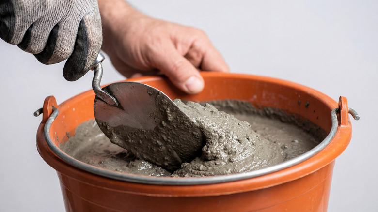 Bir kovadaki betonu malayla karıştıran kişi