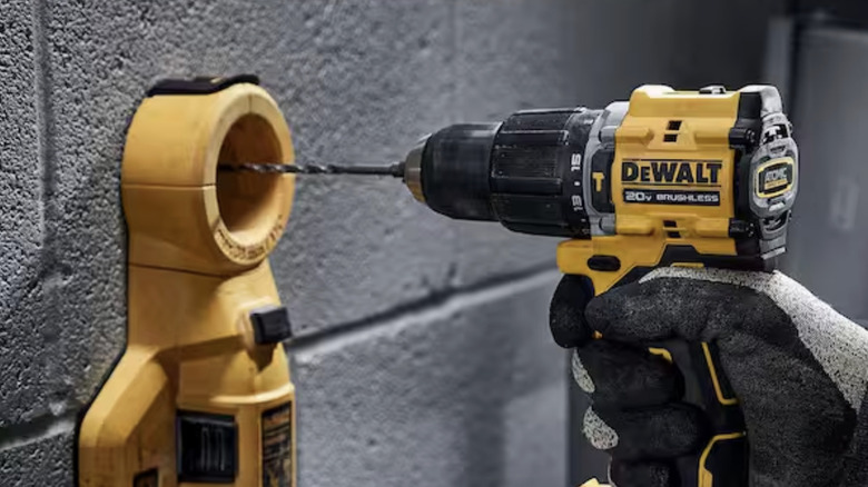 Dewalt darbeli matkabını tutan bir el.