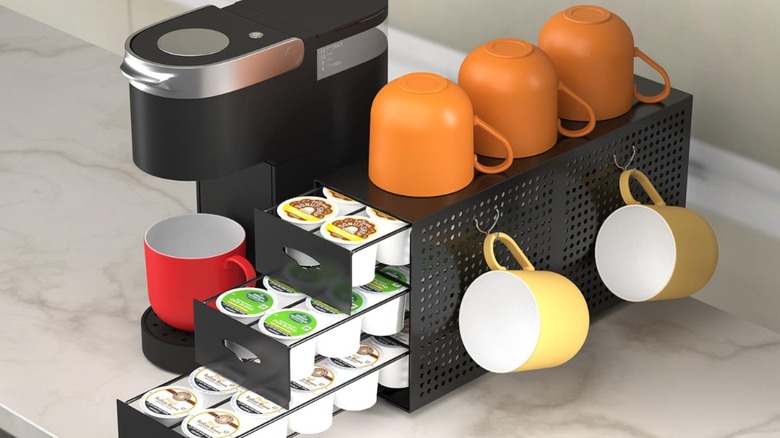 Üzerinde turuncu, sarı ve kırmızı bardaklar ve K-Cup'larla dolu çekmeceler bulunan Amazon Keurig organizatörü